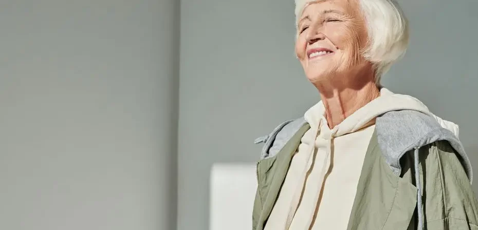Femme senior élégante souriant au soleil, vêtue d'une tenue décontractée stylée à l'intérieur.
