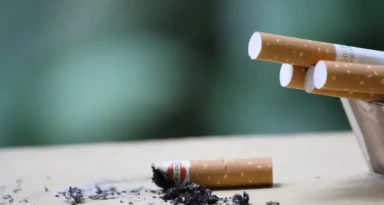 Cigarette avec des cendres sur une surface, mettant en évidence l'usage du tabac et les risques pour la santé.