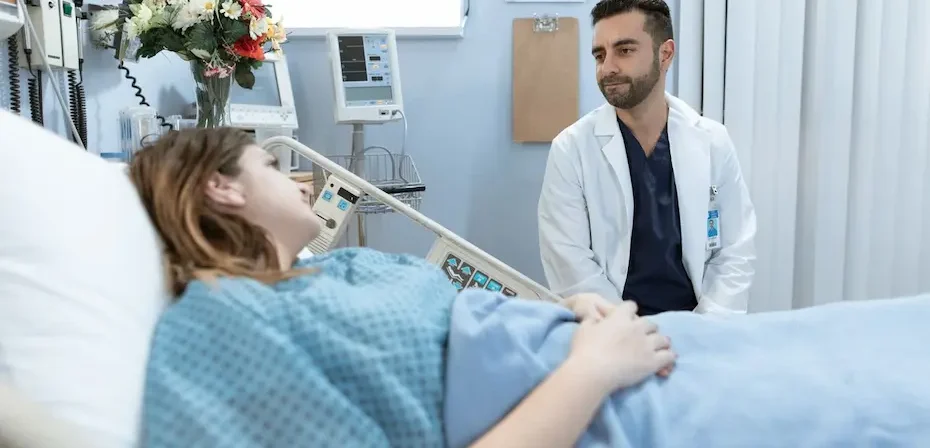 Une dame allongée sur un lit d'hôpital qui écoute son médecin qui lui parle