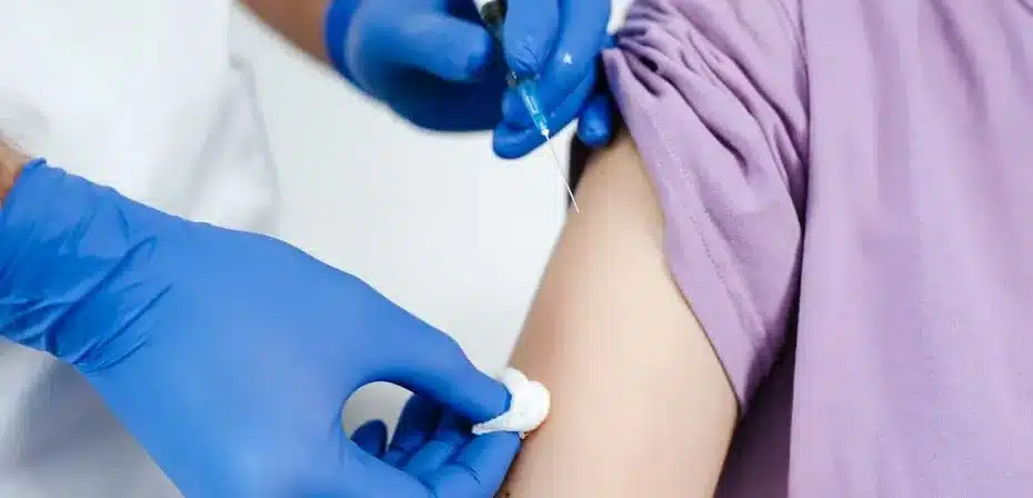Gros plan sur un professionnel de la santé administrant une injection de vaccin dans le bras d'un patient.