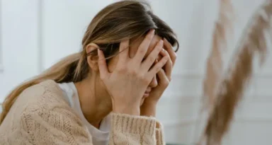Une jeune femme qui se tient la tête.